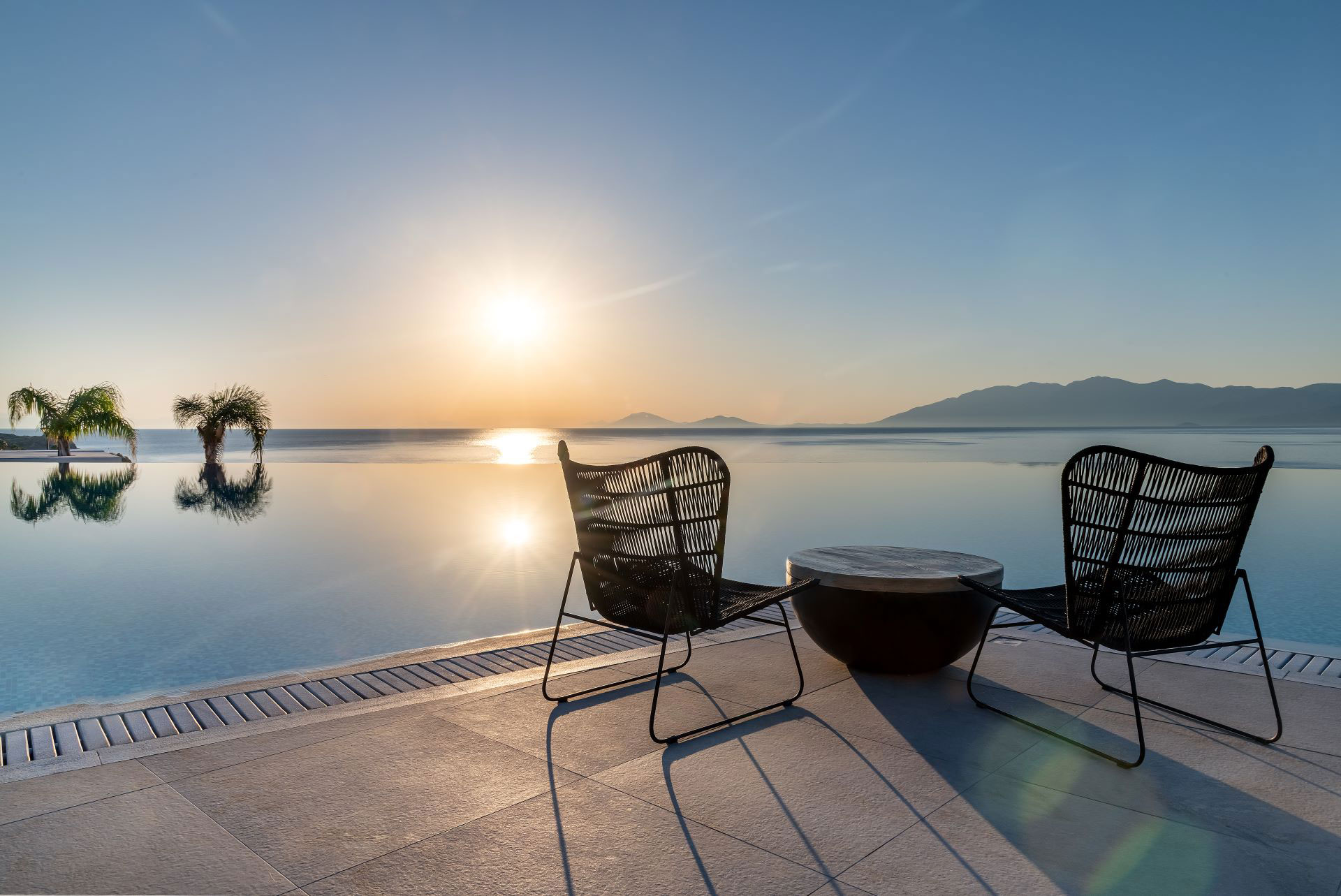 
Table with chairs in front of the pool at sunrise
